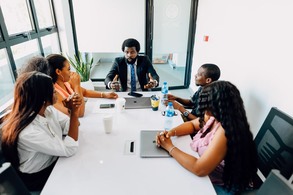 Équipe de professionnels africains en réunion de travail autour d'une table dans un bureau moderne à Lagos