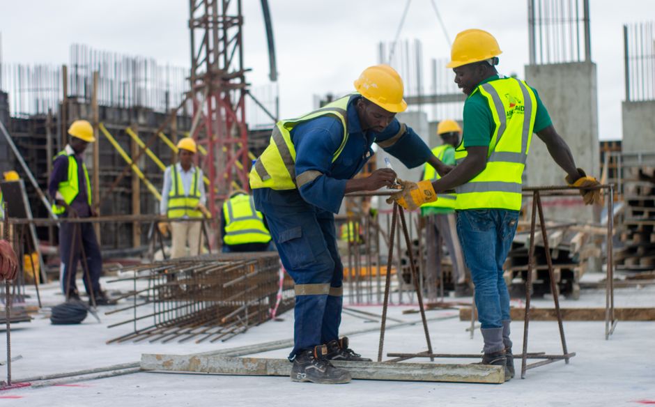Ouvriers casqués sur un chantier de construction en Afrique, illustrant les marchés de travaux de la coopération internationale