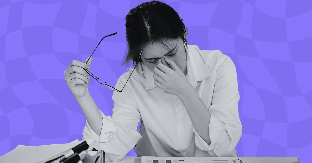 An overwhelmed bid manager at a laptop surrounded by tender documents