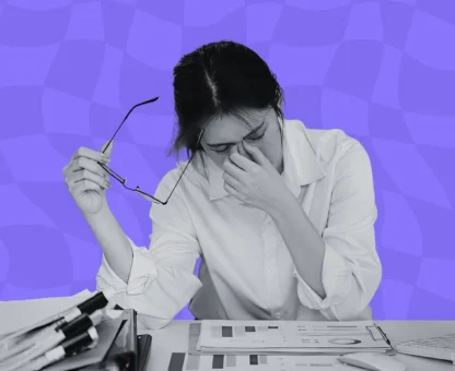 An overwhelmed bid manager at a laptop surrounded by tender documents