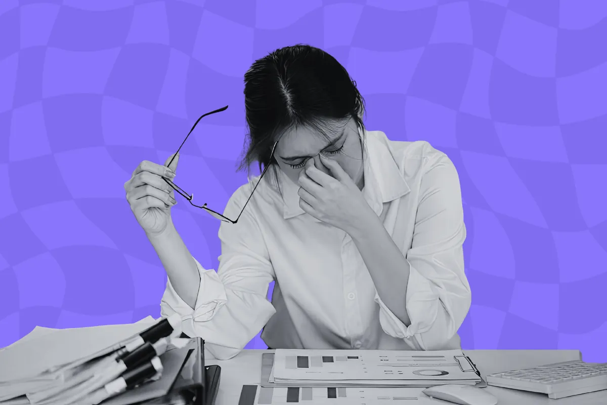 An overwhelmed bid manager at a laptop surrounded by tender documents