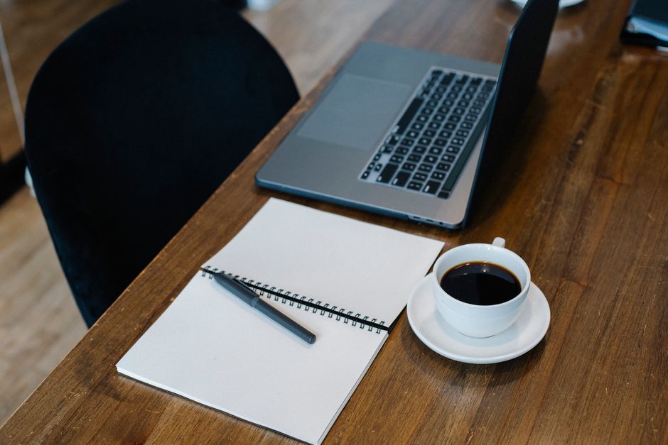 Ordinateur portable, carnet de notes et stylo posés sur un bureau en bois pour la rédaction d'une note technique